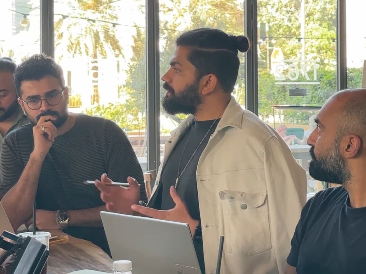 Asher standing at the table, mid-explanation, during a working session
